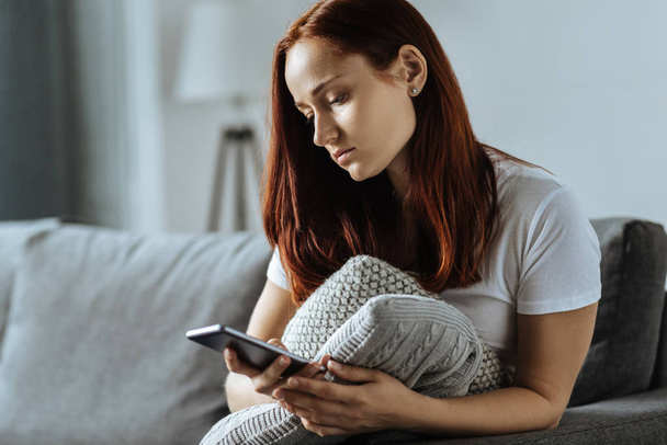 Sad young woman holding her smartphone - Photo, Image