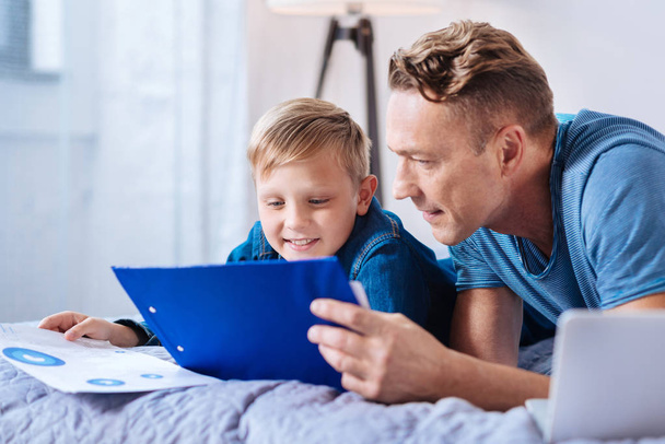 Pleasant father and son studying school materials together - Foto, afbeelding