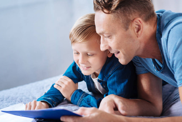 Little son and father reading together on bed - Foto, Imagem