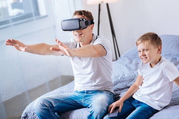 Happy man playing with a VR headset on bed - Foto, afbeelding