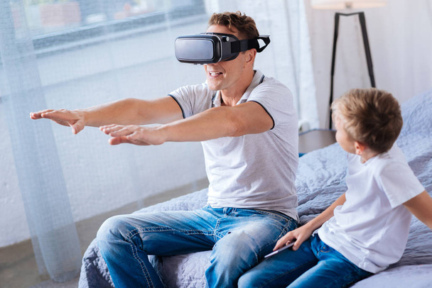 Передчасний хлопчик дивиться, як його батько грає з гарнітурою VR
 - Фото, зображення