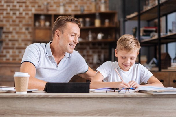 Caring father supervising his son doing homework - Foto, afbeelding