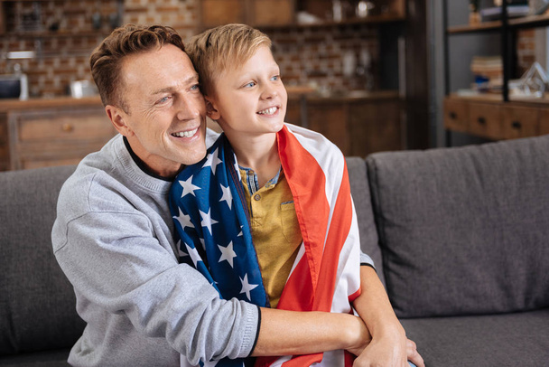Happy father hugging his son in US flag - Фото, изображение