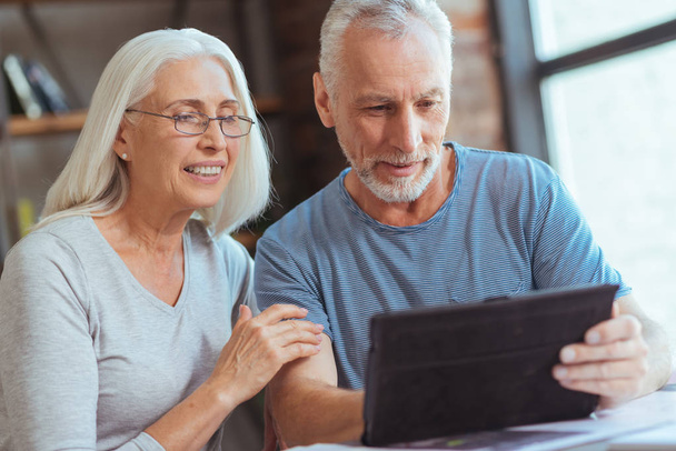 Delighted retired couple using tablet at home - Photo, Image