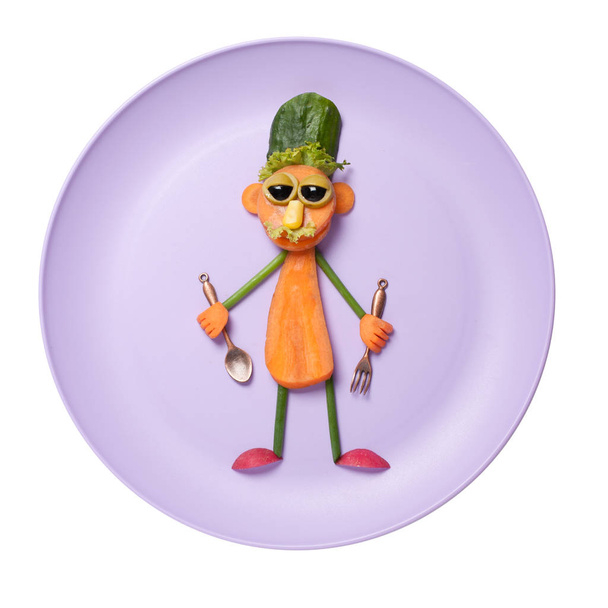 Wortel chef-kok met lepel en vork op paarse plaat - Foto, afbeelding