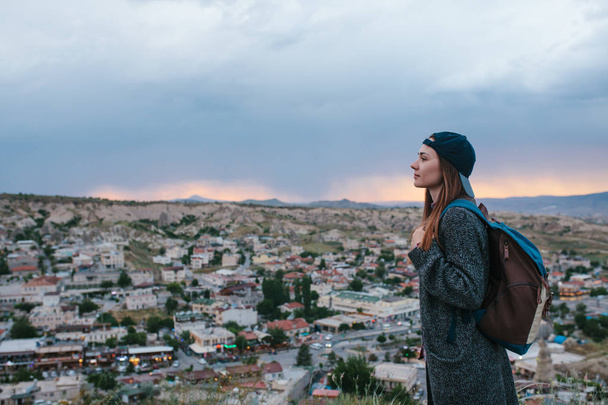 Mladá žena turistické stojí na pozadí západu slunce nad město Göreme v Turecku. Kappadokie. Turistika, odpočinek, dovolenou. - Fotografie, Obrázek