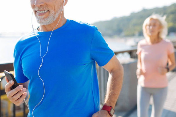Close up of senior man listening to music while running - Foto, immagini