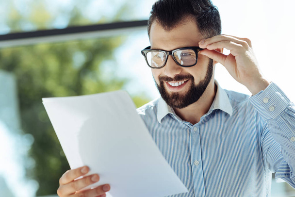 Bearded young man looking at documents and smiling - Foto, Bild