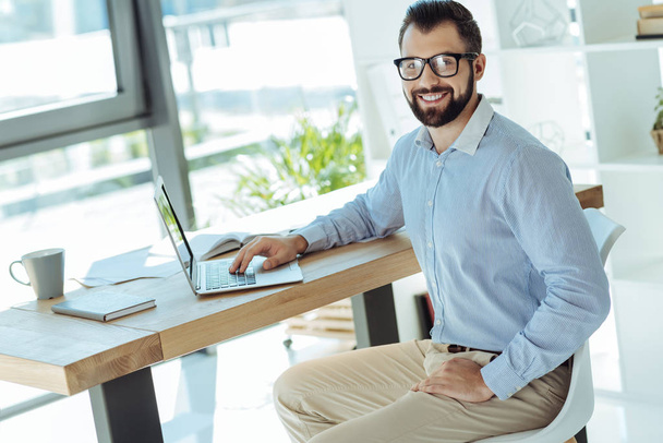 Smiling man working posing while working on laptop - Zdjęcie, obraz