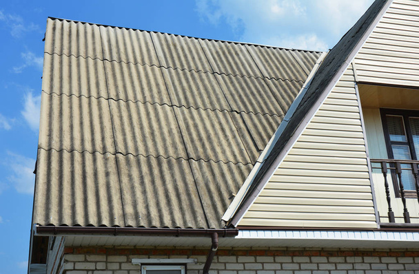 Gros plan sur les zones problématiques pour la construction de toitures d'angle de toit en amiante de maison. Toit de réparation. gouttières, gouttière, élimination de l'amiante
.  - Photo, image