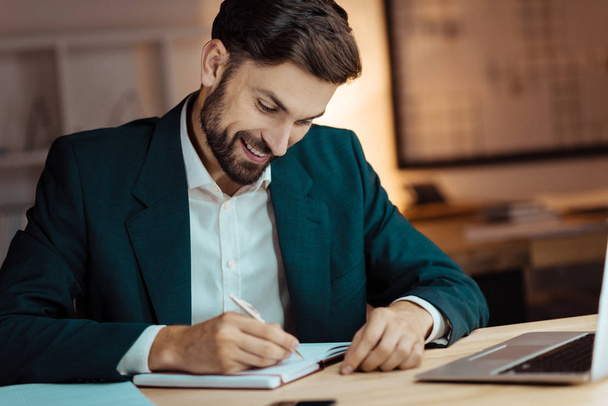 Positive delighted male person writing notes - Foto, Bild