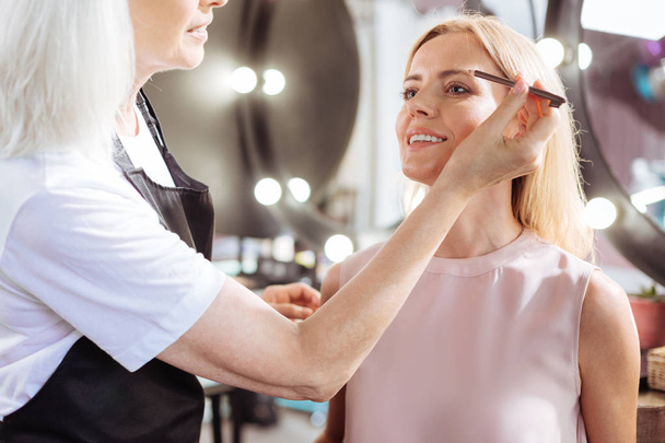 Senior woman penciling her clients eyebrows - Фото, изображение