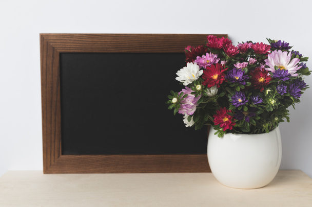 flores en jarrón y tablero en blanco
 - Foto, imagen