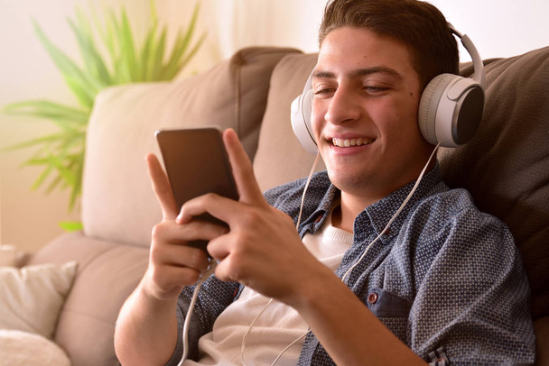 Teenager watching multimedia content with headphones sitting on  - Zdjęcie, obraz