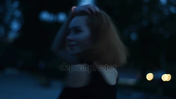 feliz chica sonriente mira a la cámara y camina tarde en la noche en la calle
 - Metraje, vídeo