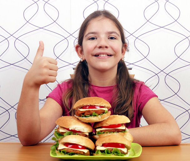 niña feliz con hamburguesas y el pulgar hacia arriba
 - Foto, Imagen