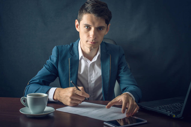 Businessman signs important legal documents on the desktop with Cup of coffee - Photo, image