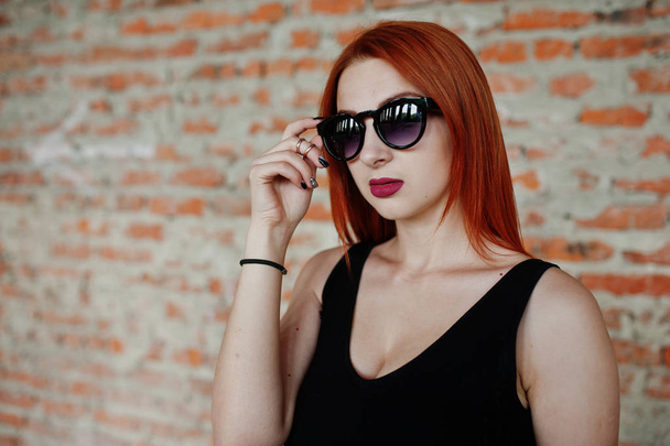Red haired stylish girl in sunglasses wear in black, against aba - Foto, afbeelding