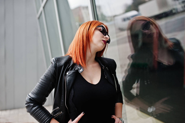 Red haired stylish girl in sunglasses wear in black, against lar - Photo, Image