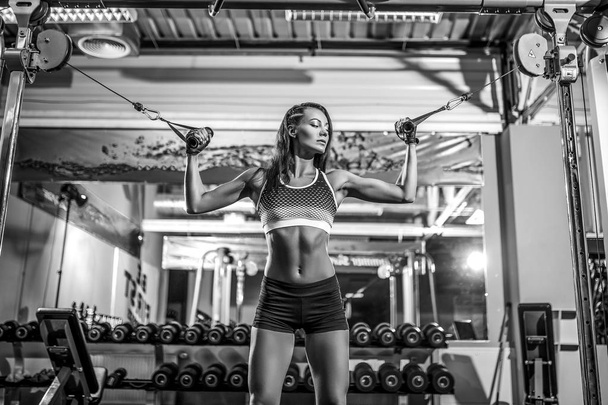 woman flexing muscles on cable machine in gym - Photo, Image