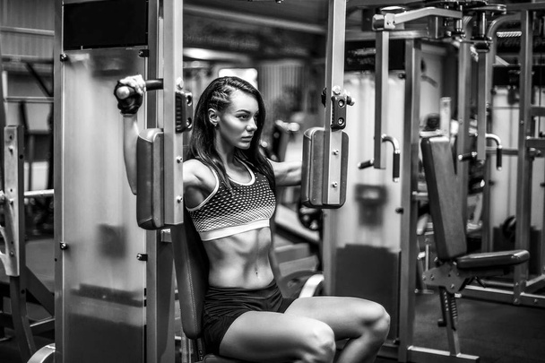 Young and sporty woman using pectoral fly machine - 写真・画像