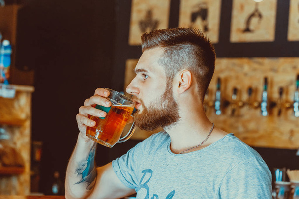 Handsome young man with a beard drinking beer   - Φωτογραφία, εικόνα