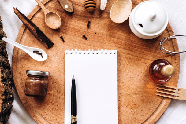 кухонная утварь, ноутбук и ручка на круглом деревянном пне
 - Фото, изображение