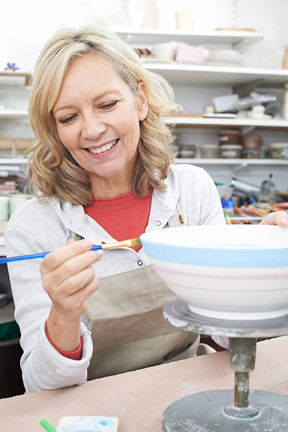 Mature Woman Decorating Bowl In Pottery Class - Foto, afbeelding