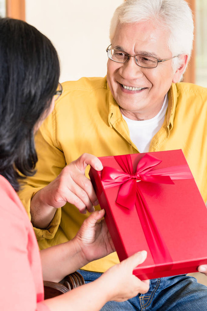Старший пара закоханих посміхаючись утримуючи подарунок - Фото, зображення
