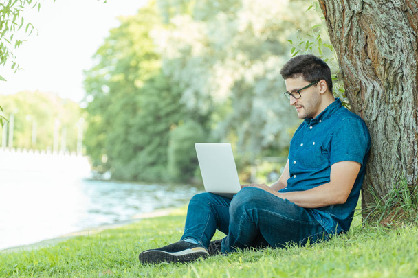Man with laptop sitting outdoors in nature - Foto, Imagem