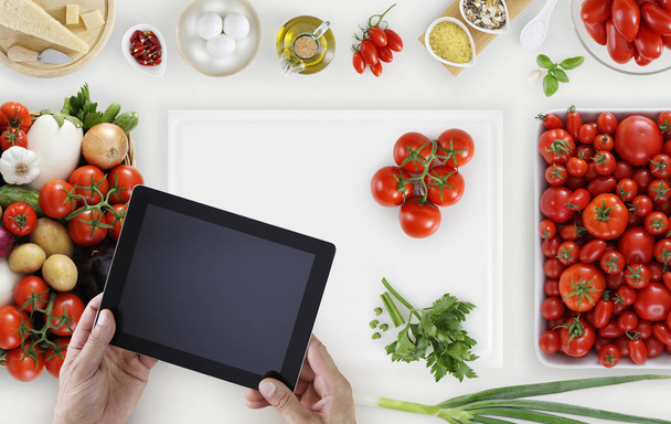 руки з цифровим планшетом зверху на білій обробній дошці з вегетаріанцями
 - Фото, зображення