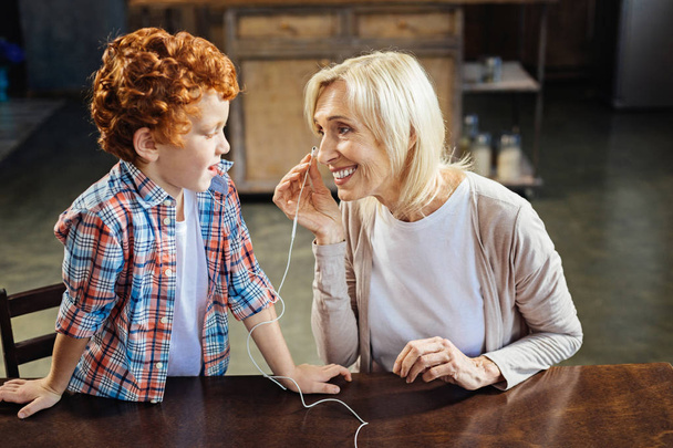 Redhead little boy sharing earphones with granny - Foto, Imagem