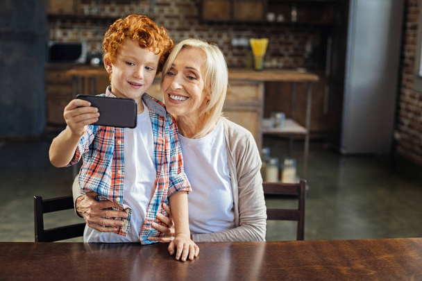 Adorable redhead kid taking selfie with granny - Foto, afbeelding
