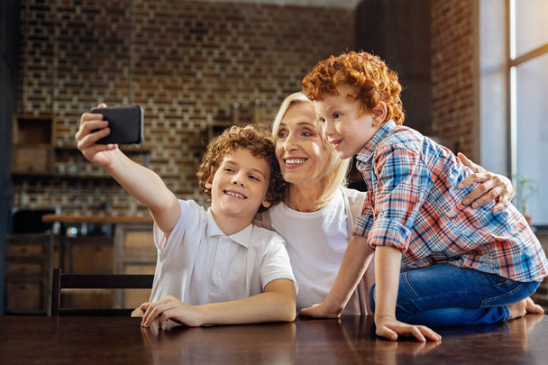 Grandkids taking selfies with cheerful grandma - 写真・画像