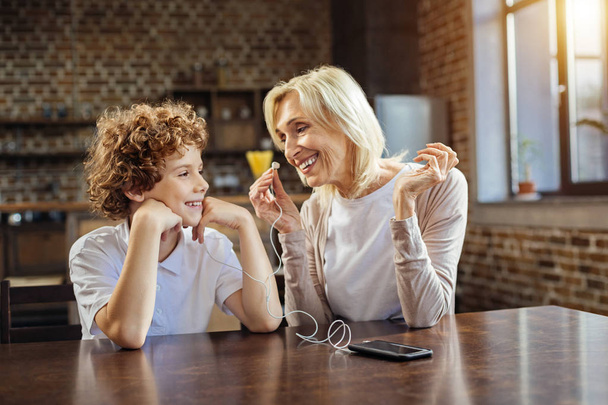 Positive elderly lady and her grandson listening to music together - Photo, Image