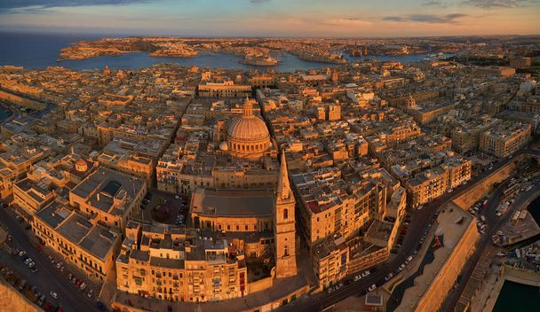 Воздушный, панорамный вид на исторические три города над Валлеттой в золотом свете. Туристическое направление. Исторический центр острова Мальта с воздуха. Каменные памятники Мальты, освещенные заходящим солнцем
 - Фото, изображение