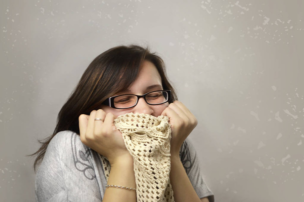 Woman loves clothes. Happy woman in glasses adores knitted scarf. Person enjoys shopping and hugs the purchases. Woman got a discount on sale and bought favorite clothe. Shopper with clean background - Zdjęcie, obraz