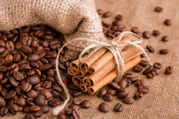 Coffee beans and cinnamon on a background of burlap. Roasted coffee beans background close up. Coffee beans pile from top with copy space for text. Seasoning. Spice. Cinnamon. Badian. Coffee house. - Φωτογραφία, εικόνα