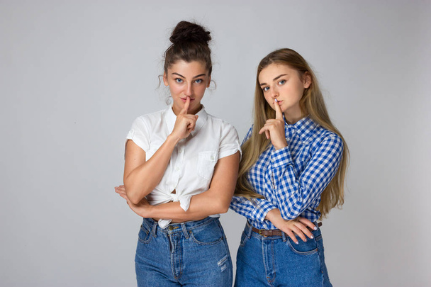 Zwei junge Schwestern mit einem Finger auf den Lippen - schweigende Geste. Nahaufnahme einer jungen Frau, die "shhh" sagt, - Foto, Bild