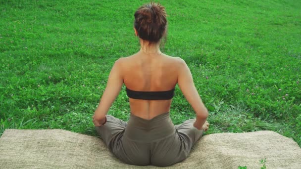 Ragazza siede nel tappetino yoga e facendo una delle pose yoga
 - Filmati, video