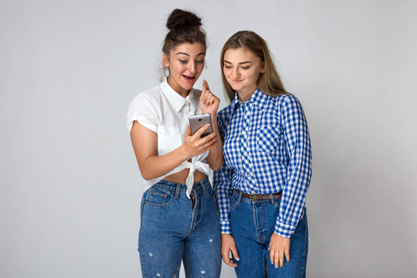 Portrait of a  emotions, expressions, success and people concept - happy two young sisters or teenage girls celebrating victory  standing over gray background - Foto, Imagen