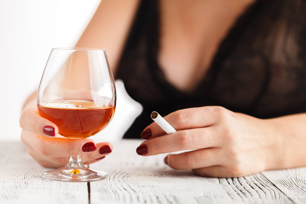 Woman in lingerie sitting at a table and drinking alcohol - Foto, afbeelding