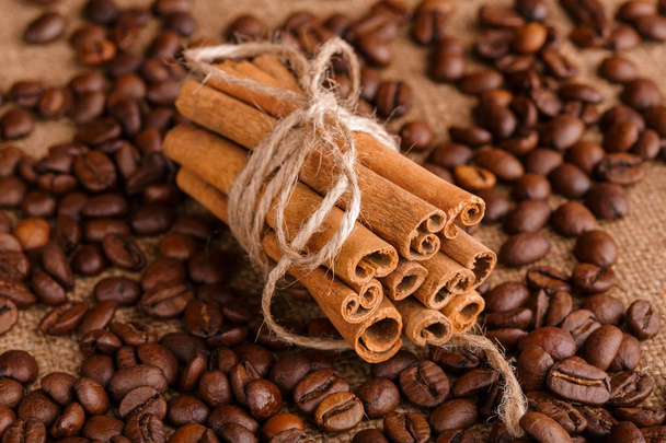 Coffee beans and cinnamon on a background of burlap. Roasted coffee beans background close up. Coffee beans pile from top with copy space for text. Seasoning. Spice. Cinnamon. Badian. Coffee house. - Photo, Image