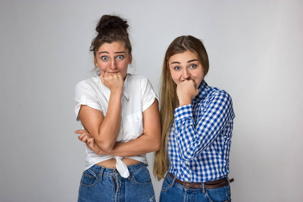 Twee jonge zussen zijn hun vuisten bijten over grijze achtergrond - Foto, afbeelding