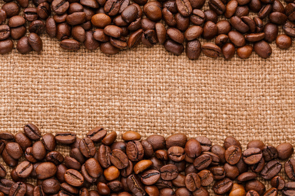 coffee beans on burlap background. roasted coffee beans isolated in white background. Roasted coffee beans background close up. Coffee beans pile from top on white background with copy space for text - Fotó, kép