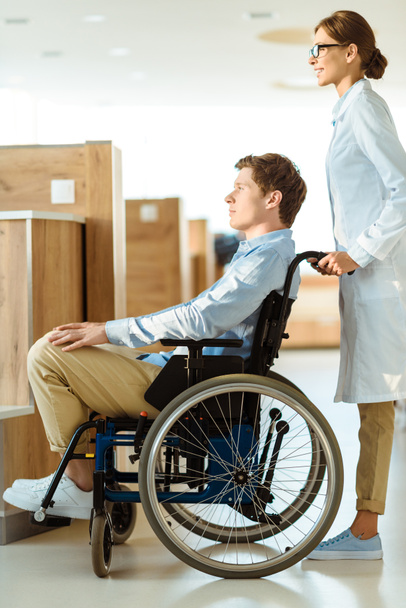 doctor rolling man in wheelchair - Foto, afbeelding