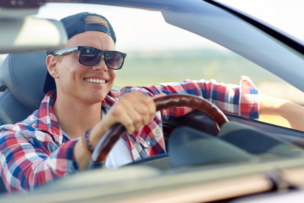 コンバーチブル車を運転の色合いで幸せな若い男 - 写真・画像