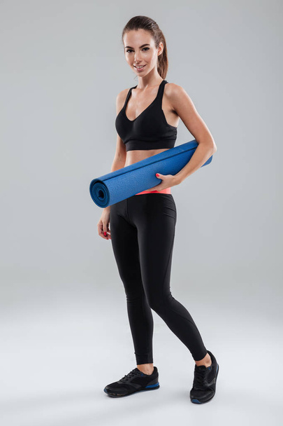 Full length image of smiling fitness woman holding fitness mat - Zdjęcie, obraz