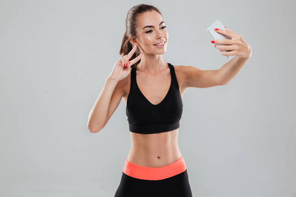 Smiling fitness woman making selfie on her smartphone - Fotó, kép