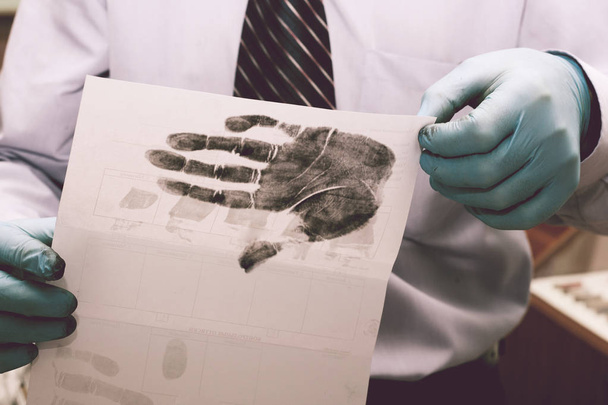 Ο ερευνητής παίρνει δακτυλικά αποτυπώματα από ο ύποπτος για το έγκλημα. Έρευνα είναι ένα έγκλημα. Έγκλημα. - Φωτογραφία, εικόνα